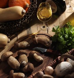 Holzbrett mit Speisepilzen, ein Messer und ein Glas Weißwein