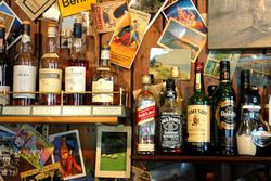 Holzwand mit Postkarten und sehr vielen Whiskyflaschen
