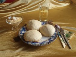 Gedeck mit Dampfnudeln, einer Schüssel mit Weinsoße und ein Glas Wein