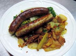 Teller mit Bratwürsten und Bratkartoffeln
